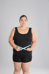 Photo of Overweight woman measuring waist before weight loss on color background