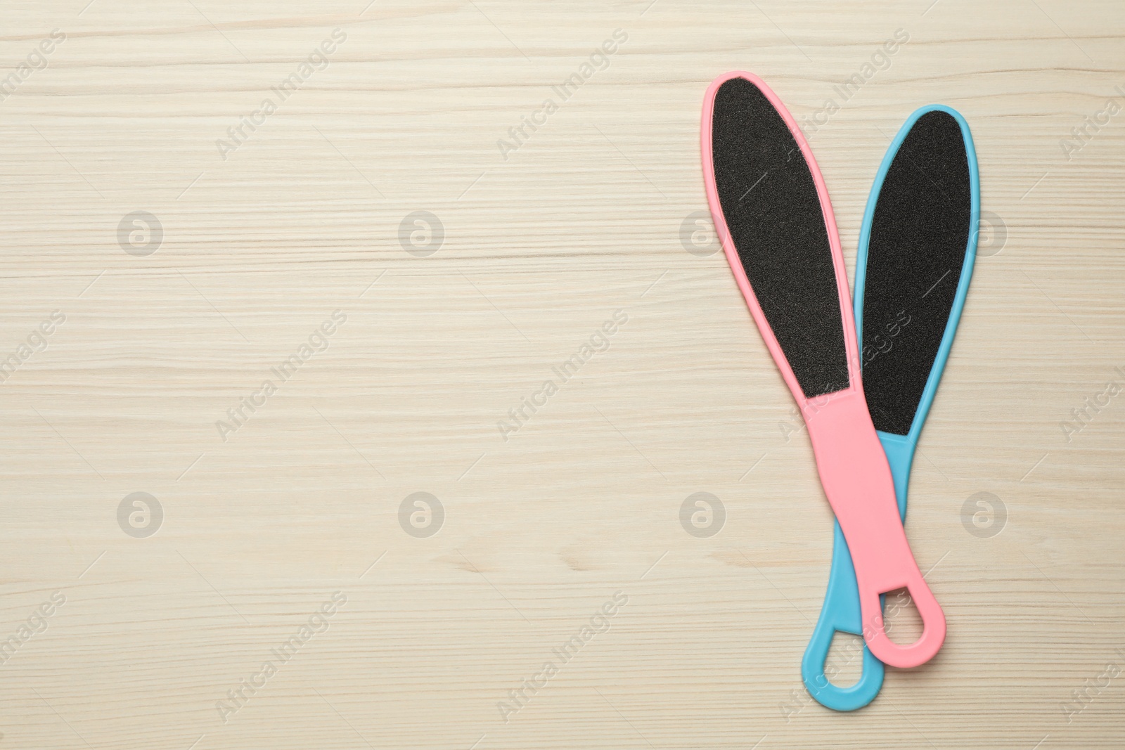 Photo of Colorful foot files on white wooden table, flat lay with space for text. Pedicure tools