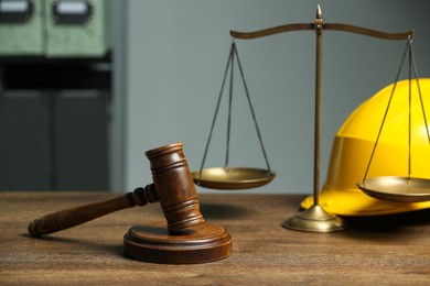 Photo of Construction and land law concepts. Gavel, scales of justice and hard hat on wooden table