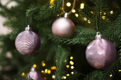 Photo of Beautiful Christmas balls hanging on fir tree, closeup