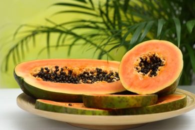 Photo of Plate with fresh juicy cut papayas on white table against blurred background, space for text