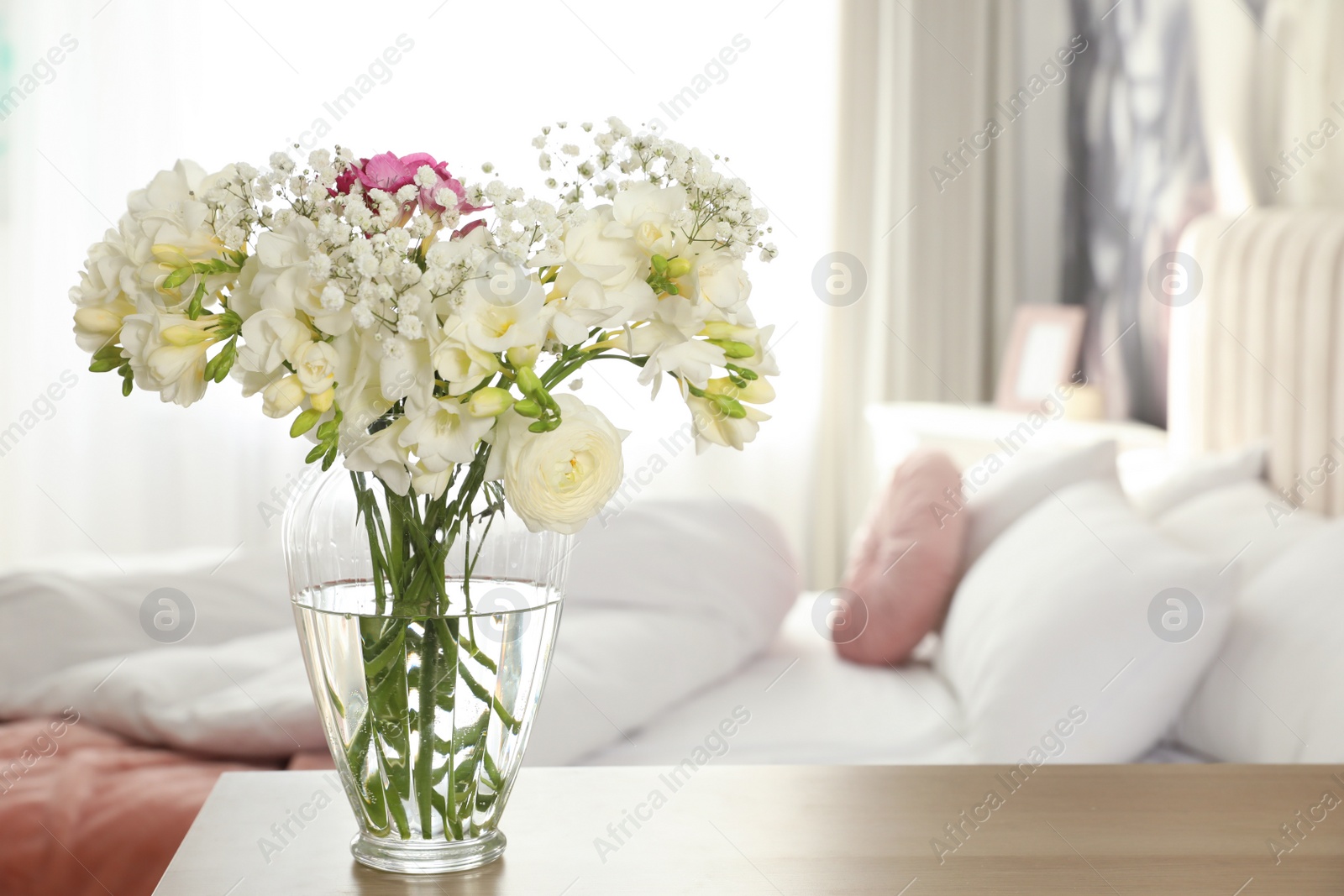 Photo of Beautiful bouquet with fresh freesia flowers on table in bedroom. Space for text