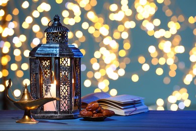 Arabic lantern, Quran, dates and Aladdin magic lamp on table against light blue background with blurred lights. Space for text