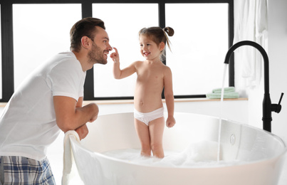 Young father with cute little daughter in bathroom