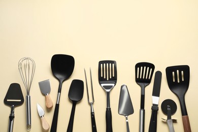 Photo of Different spatulas and other kitchen utensils on beige background, flat lay. Space for text