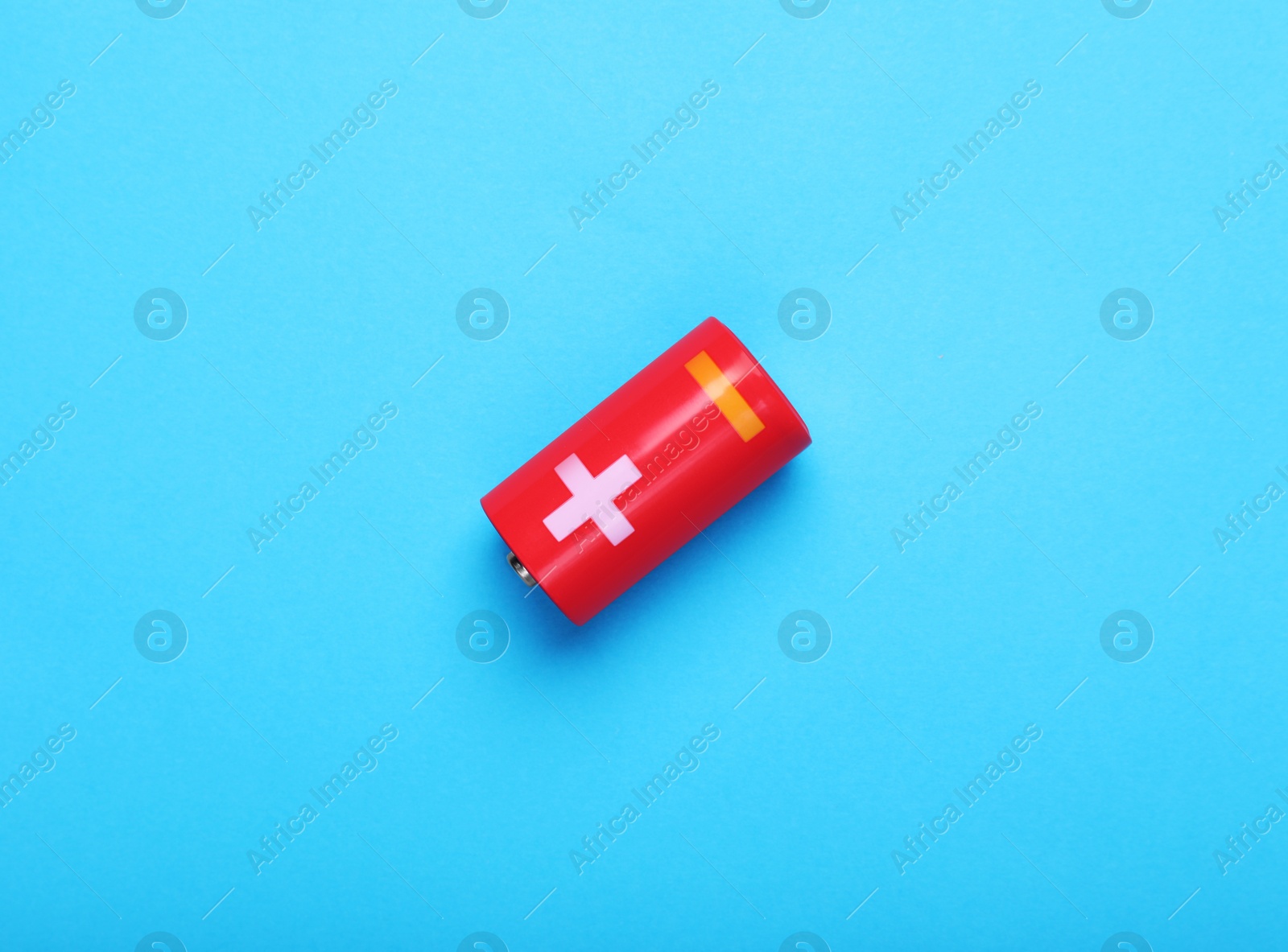 Photo of New C size battery on light blue background, top view