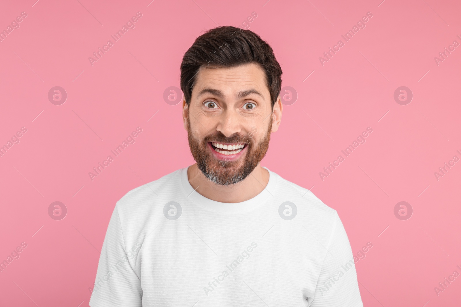 Photo of Portrait of happy surprised man on pink background