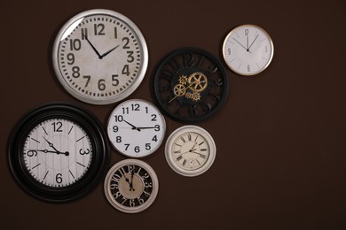 Collection of stylish clocks on brown wall