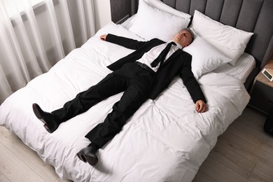 Photo of Businessman in office clothes sleeping on bed indoors