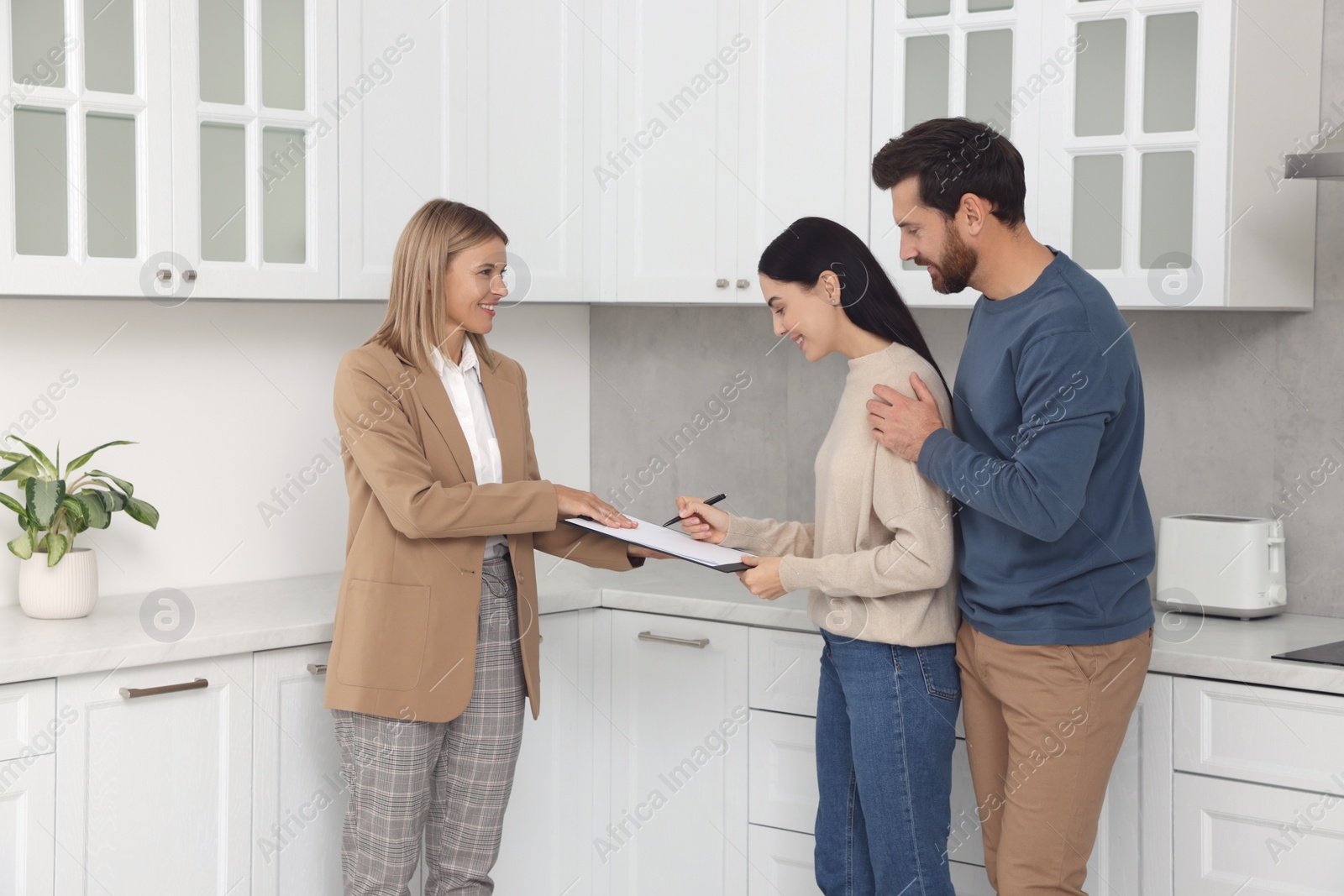 Photo of Real estate agent and couple signing contract in new apartment