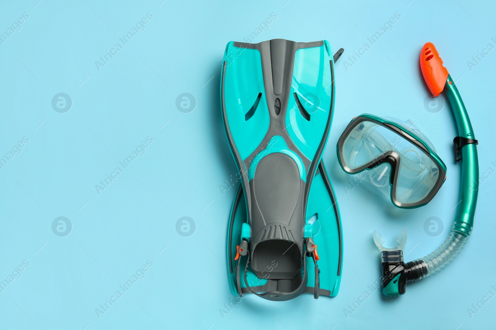 Photo of Pair of turquoise flippers and mask on light blue background, flat lay. Space for text