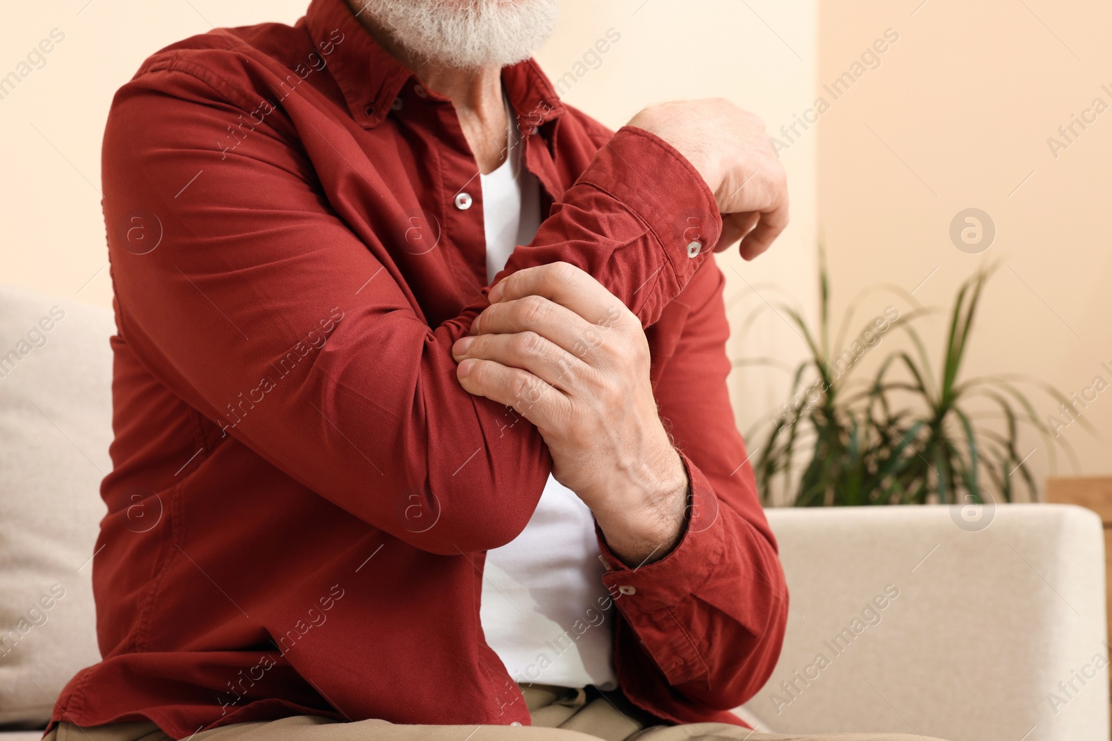 Photo of Senior man suffering from pain in his hand at home, closeup. Arthritis symptoms