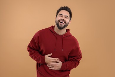 Handsome young man laughing on beige background