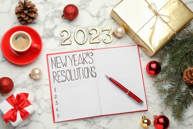 Photo of Making resolutions for 2023 New Year. Flat lay composition with notebook and festive decor on white marble table