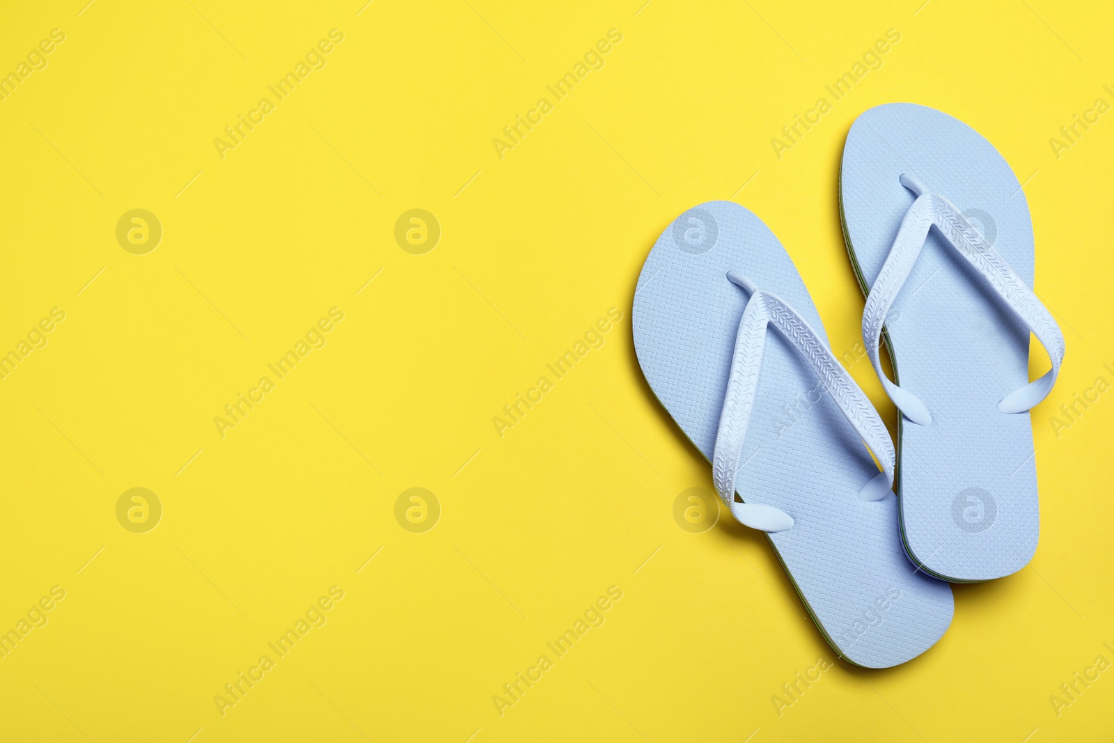 Photo of Stylish flip flops on yellow background, flat lay. Space for text