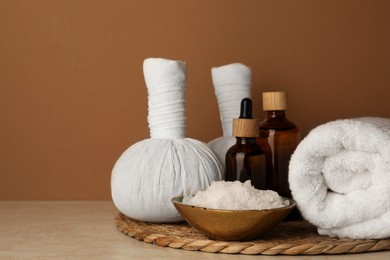 Photo of Composition with different spa products on beige table against brown background. Space for text