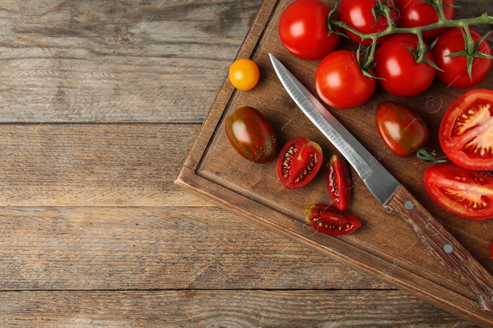 Photo of Fresh ripe tomatoes, knife and cutting board on wooden table, flat lay. Space for text