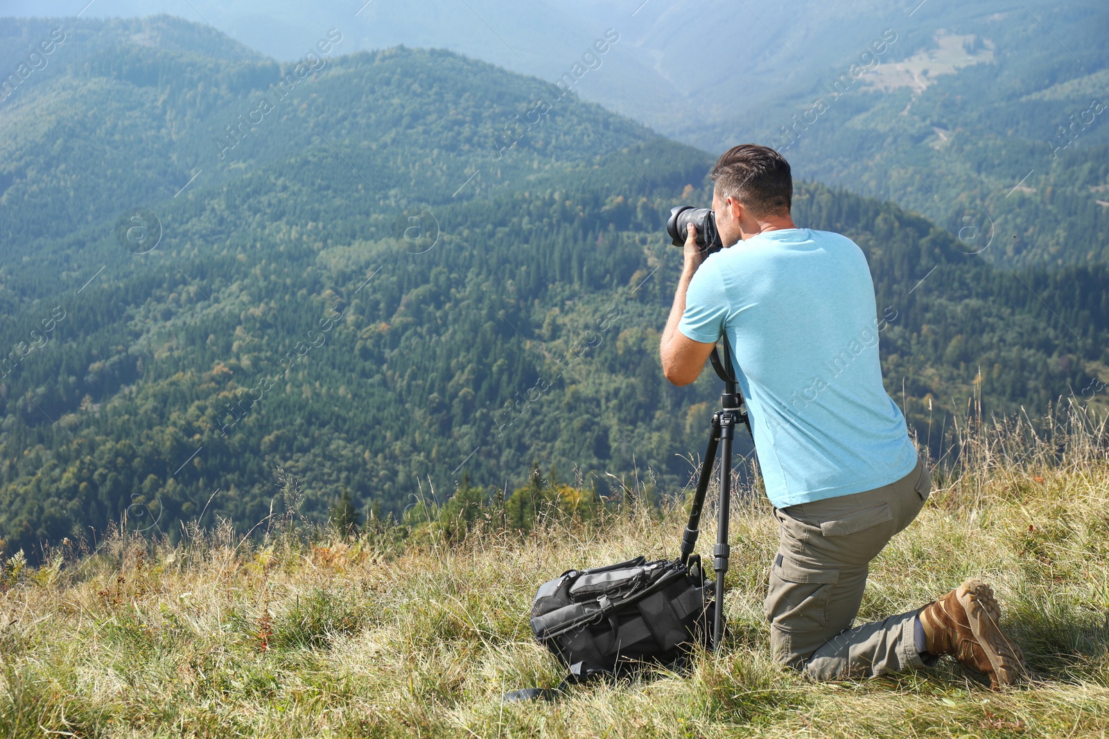 Photo of Man taking photo of mountain landscape with modern camera on tripod outdoors