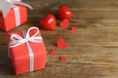 Photo of Beautiful gift box with decorative red hearts on wooden table, closeup. Space for text