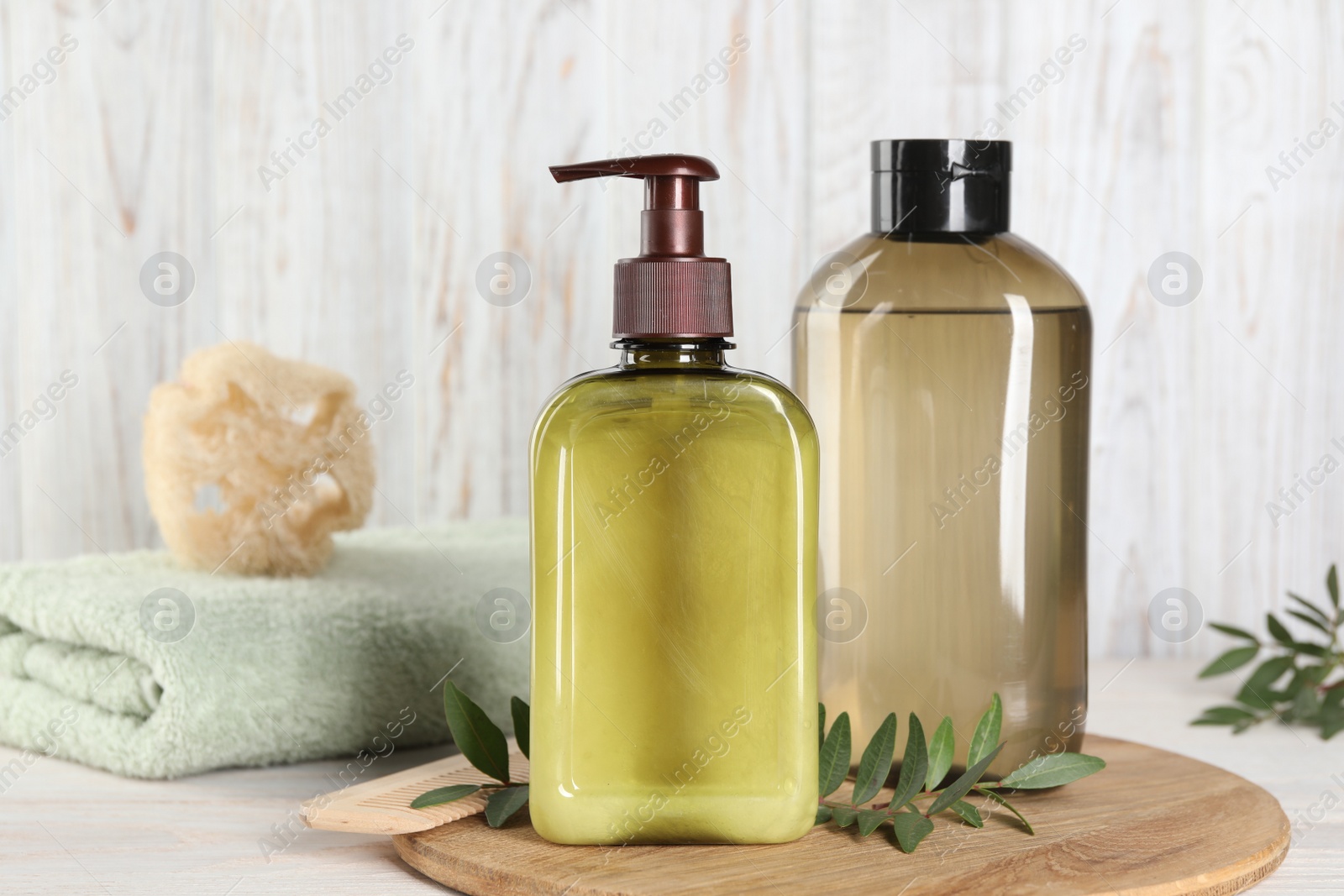 Photo of Shampoo bottles, loofah and folded towel on white wooden table