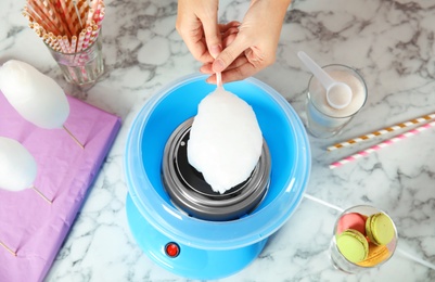 Photo of Woman making cotton candy using modern machine at table, above view