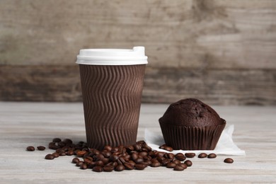 Photo of Paper cup with white lid, coffee beans and muffin on wooden table. Coffee to go