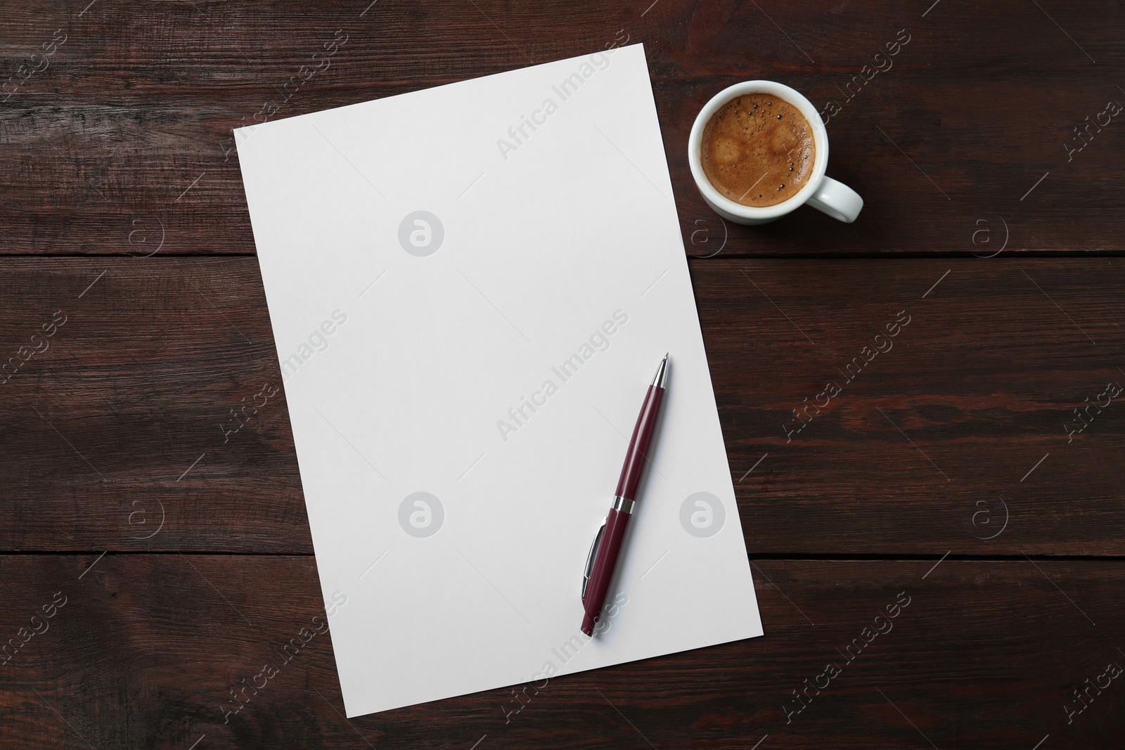 Photo of Blank paper sheet, pen and cup of coffee on dark wooden table, flat lay. Space for text