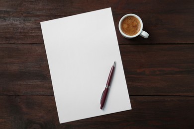 Photo of Blank paper sheet, pen and cup of coffee on dark wooden table, flat lay. Space for text