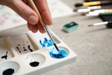 Woman painting with watercolor at grey stone table, closeup