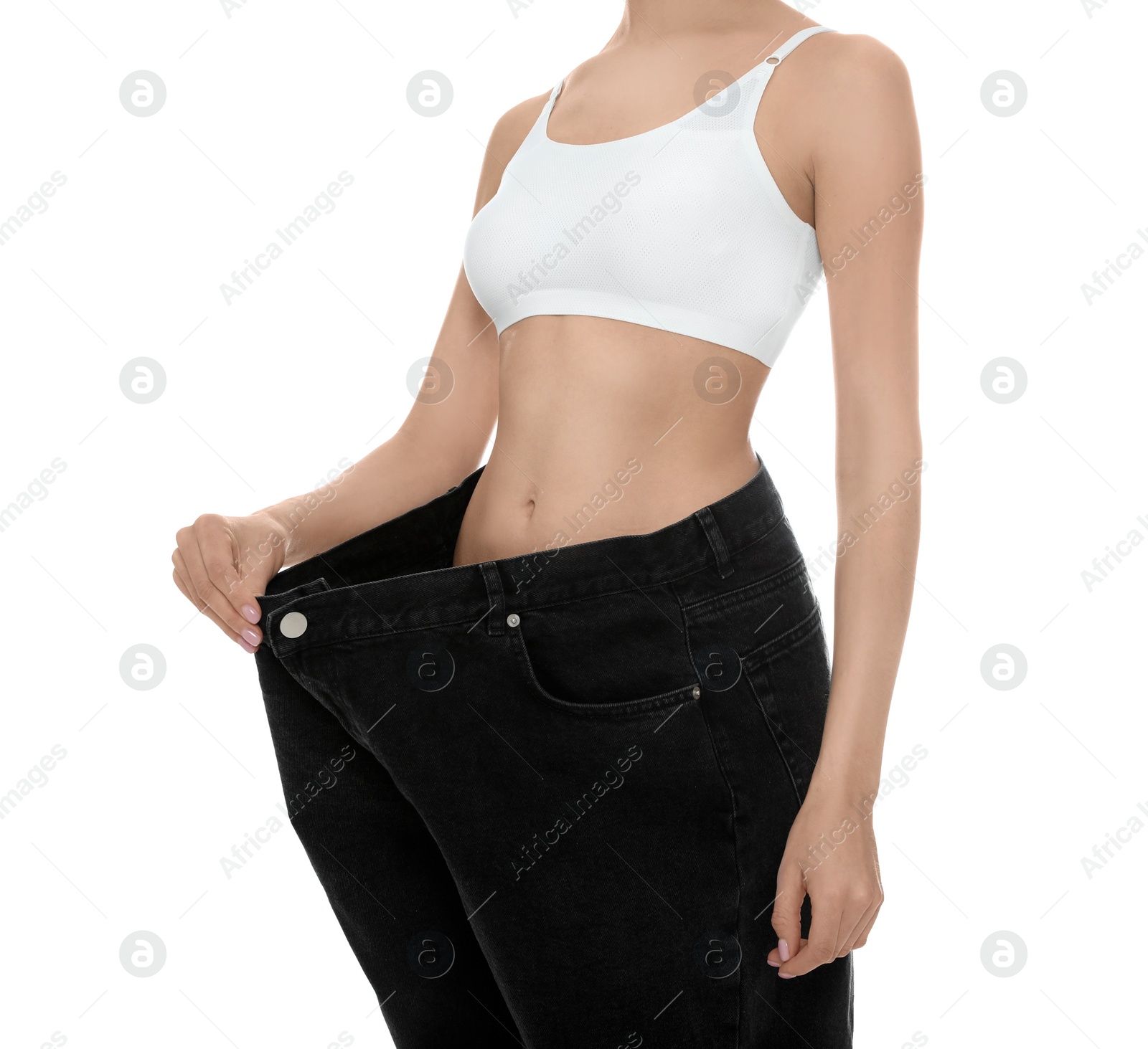 Photo of Young woman wearing big jeans after weight loss on white background, closeup