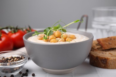 Photo of Tasty chickpea soup in bowl on white tiled table, closeup