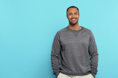 Portrait of handsome young man on light blue background, space for text