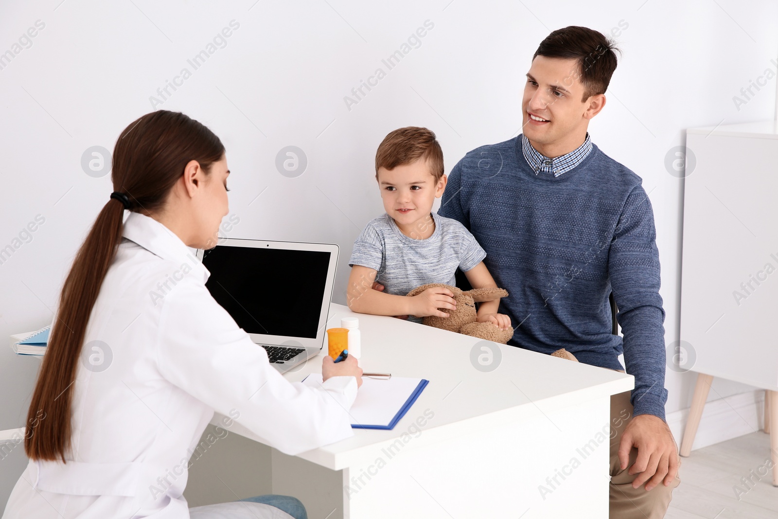 Photo of Father and son visiting pediatrician. Doctor working with patient in hospital