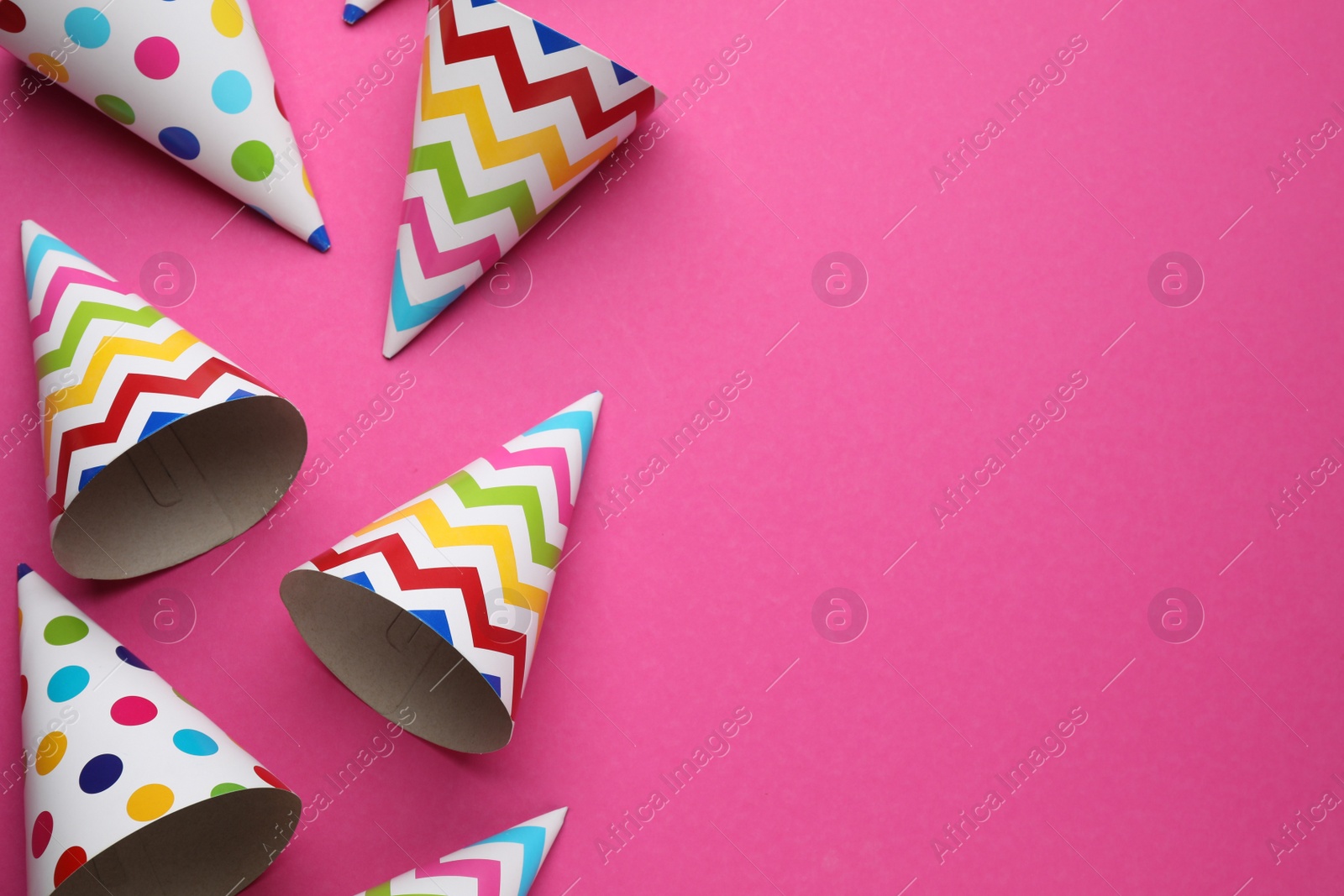 Photo of Bright party hats on pink background, flat lay. Space for text