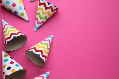 Bright party hats on pink background, flat lay. Space for text