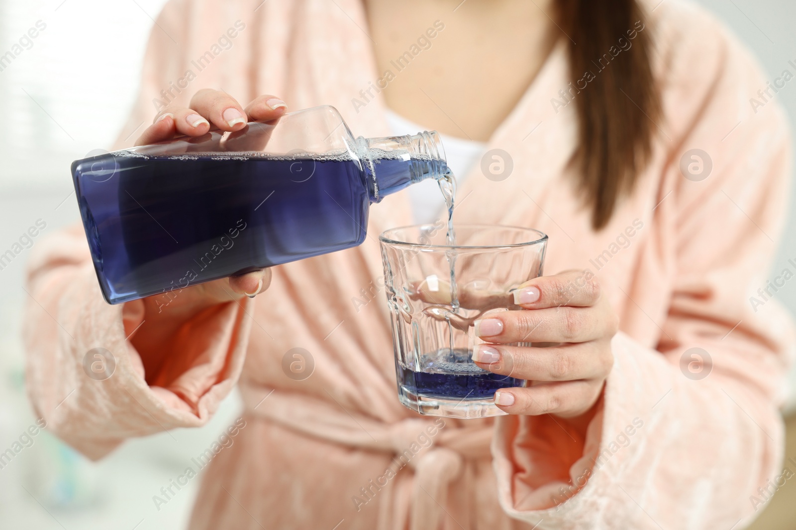 Photo of Young woman using mouthwash on light background, closeup