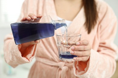 Photo of Young woman using mouthwash on light background, closeup