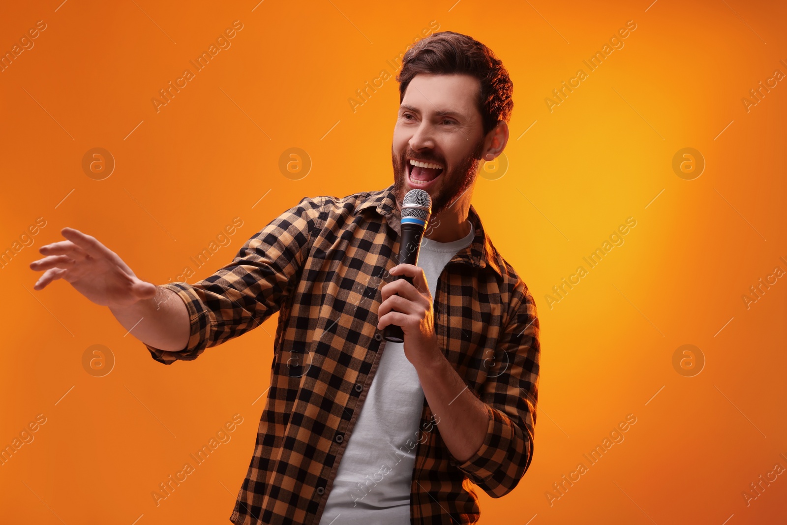 Photo of Handsome man with microphone singing on golden background