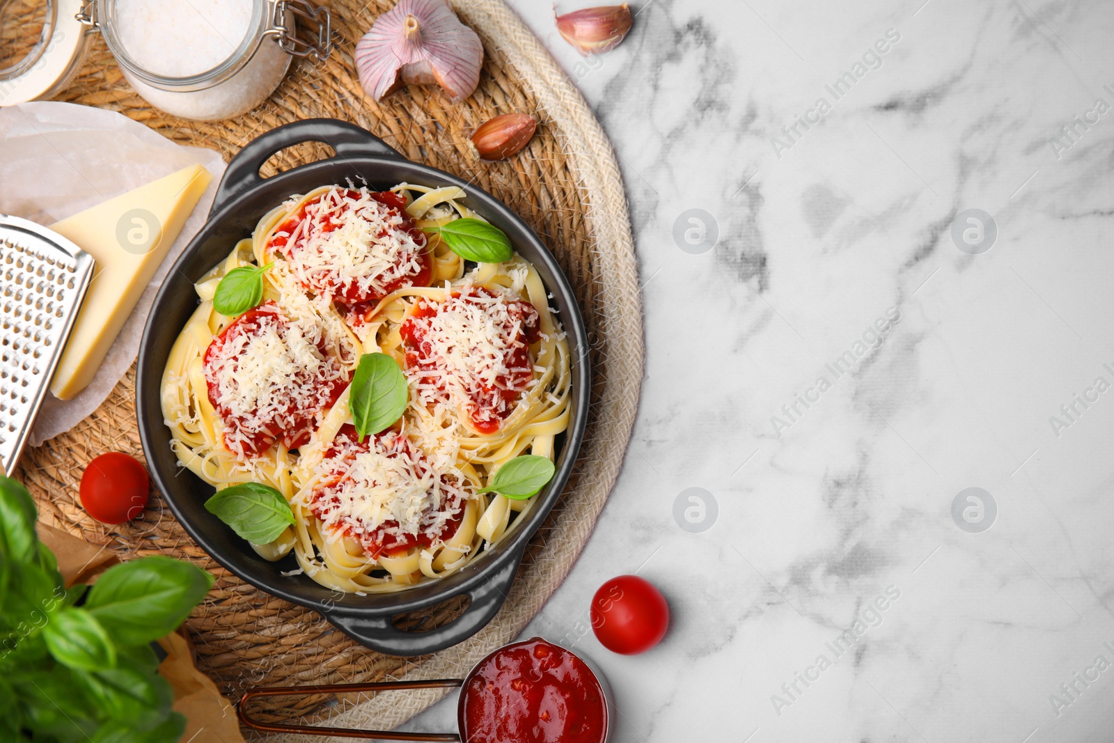 Photo of Delicious pasta with tomato sauce, basil and parmesan cheese on white marble table, flat lay. Space for text