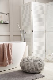 Photo of Stylish knitted pouf on floor in modern bathroom. Interior design