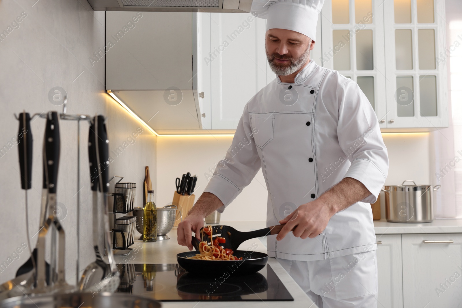 Photo of Professional chef cooking delicious pasta in kitchen