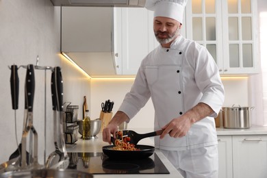 Photo of Professional chef cooking delicious pasta in kitchen