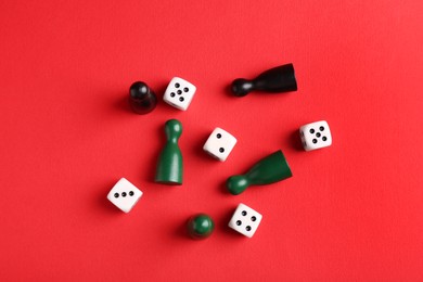 Photo of Many white dices and color game pieces on red background, flat lay