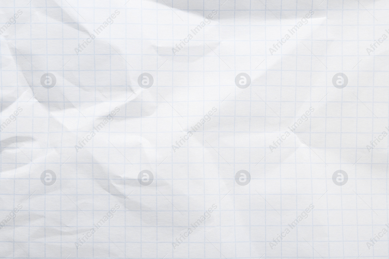 Photo of Crumpled checkered notebook sheet as background, top view