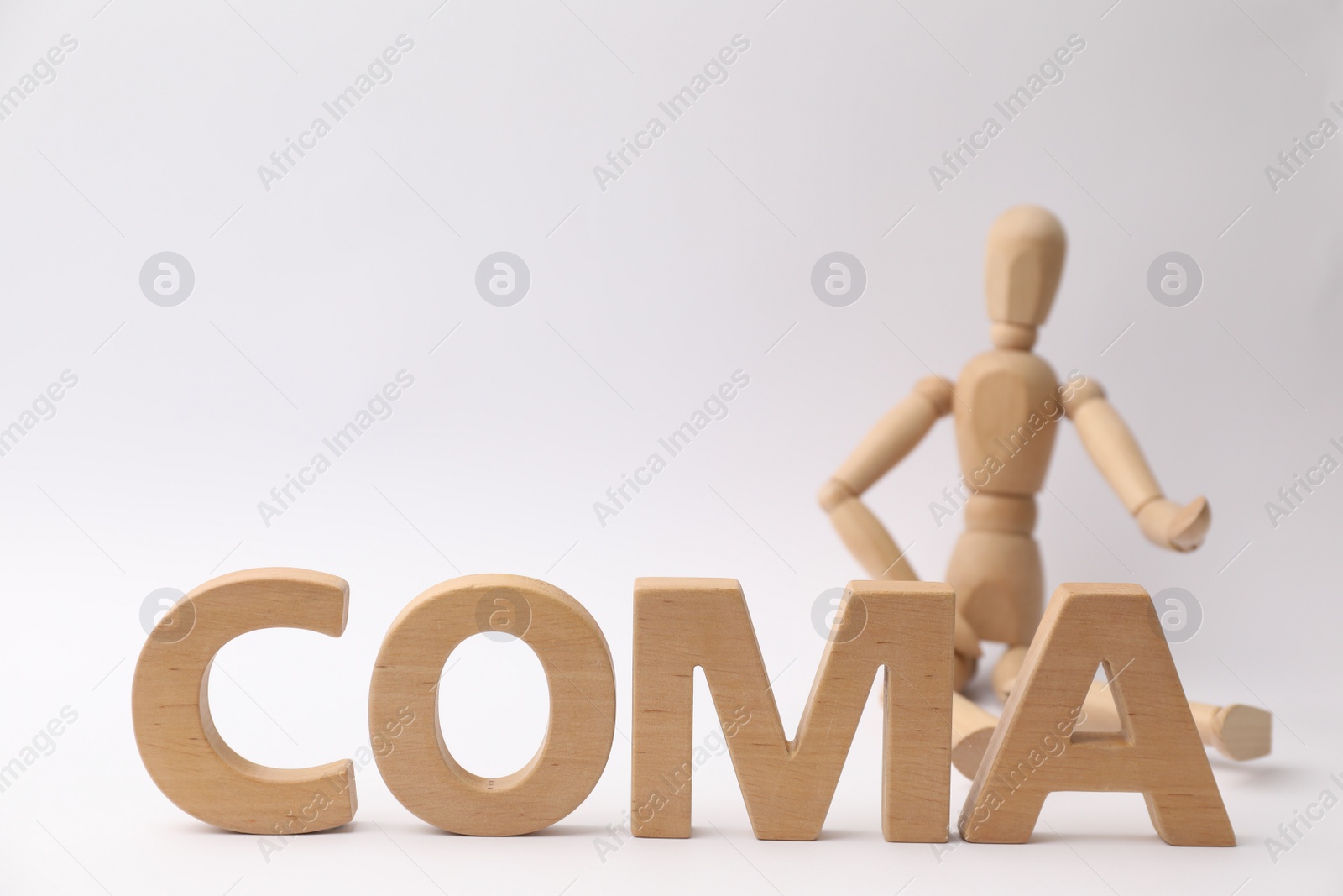 Photo of Word Coma made of wooden letters and human mannequin on light background, closeup