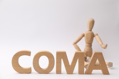 Word Coma made of wooden letters and human mannequin on light background, closeup