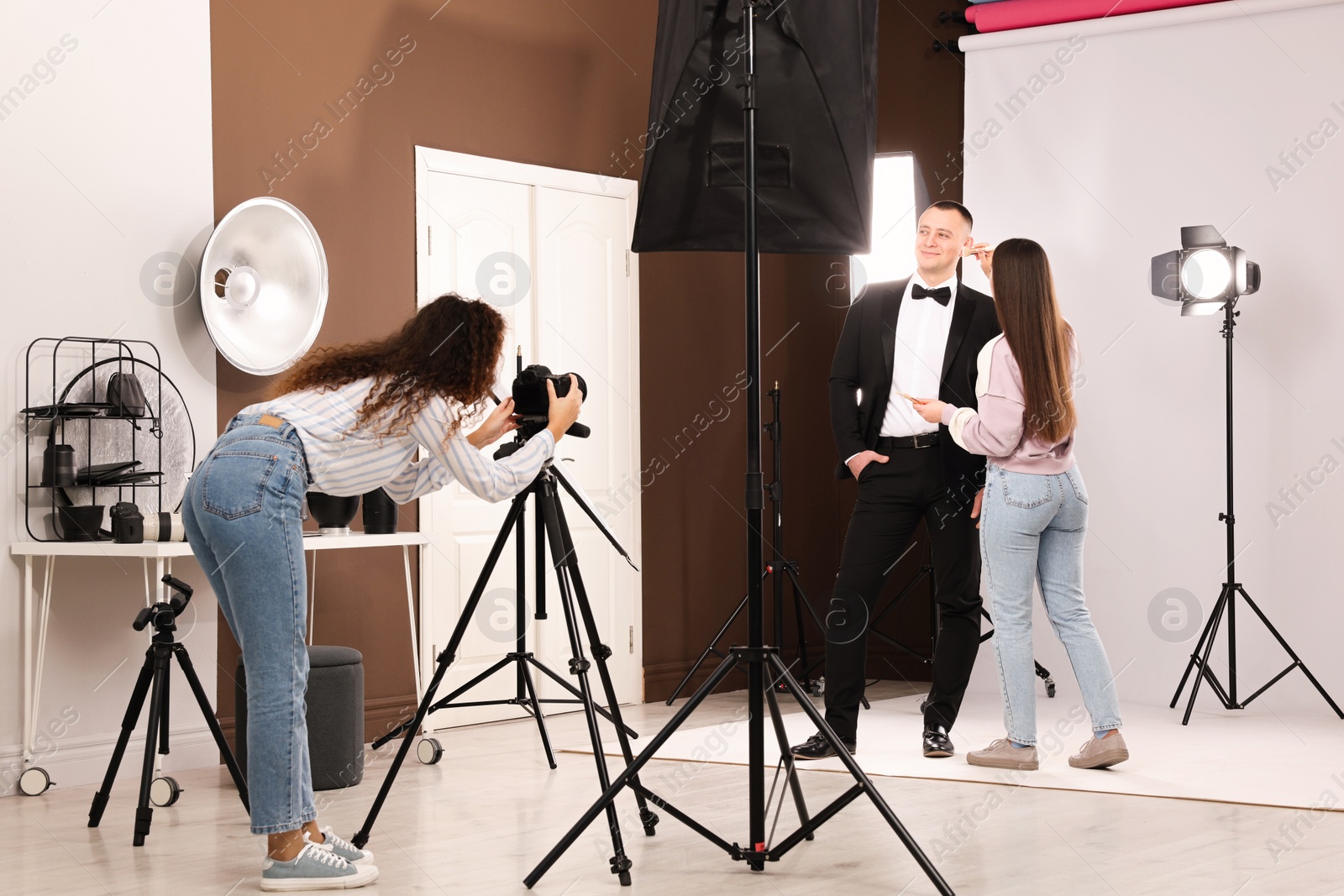 Photo of Professional photographer and makeup artist with model in studio