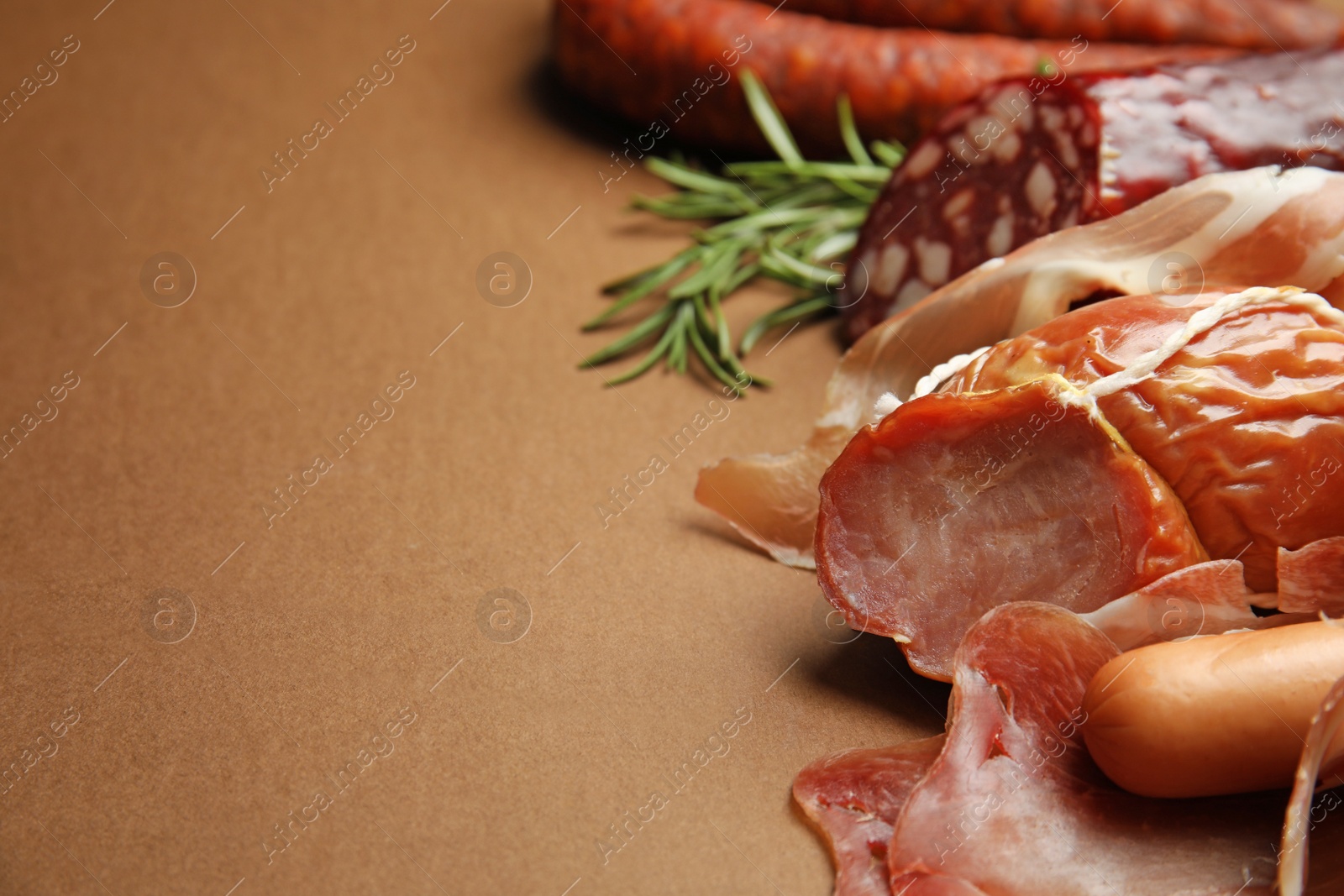 Photo of Different types of sausages on brown background, closeup. Space for text