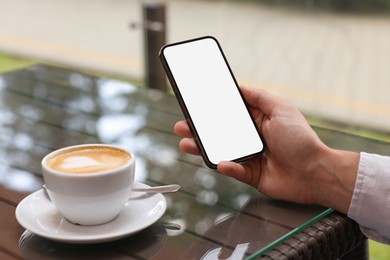 Photo of Man using mobile phone at table in outdoor cafe, closeup
