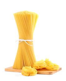 Photo of Wooden board with spaghetti and tagliatelle pasta isolated on white